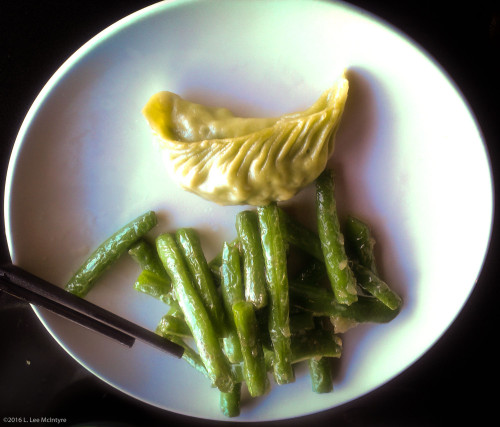A veggie dumpling and some green beans with garlic sauce